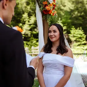 Sarah smiling at her soon to be husband as he reads his vows to her at the altar