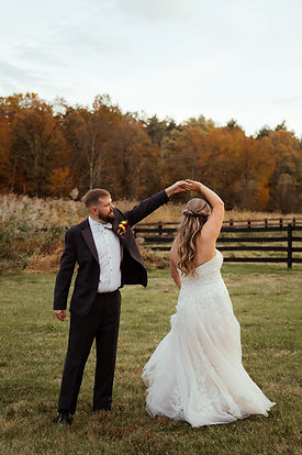 Husband spinning his wife in a field on their wedding day