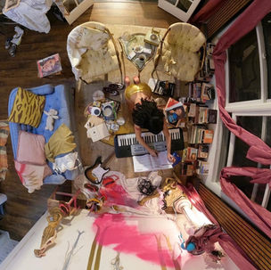 Arial shot of a girl writing and playing music in a messy room