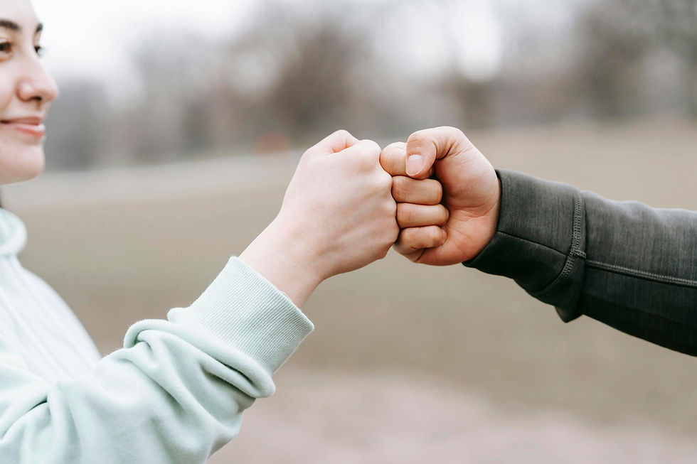 crop-anonymous-cheerful-woman-and-man-giving-fist-bump-to-each-other-on-blurred-background