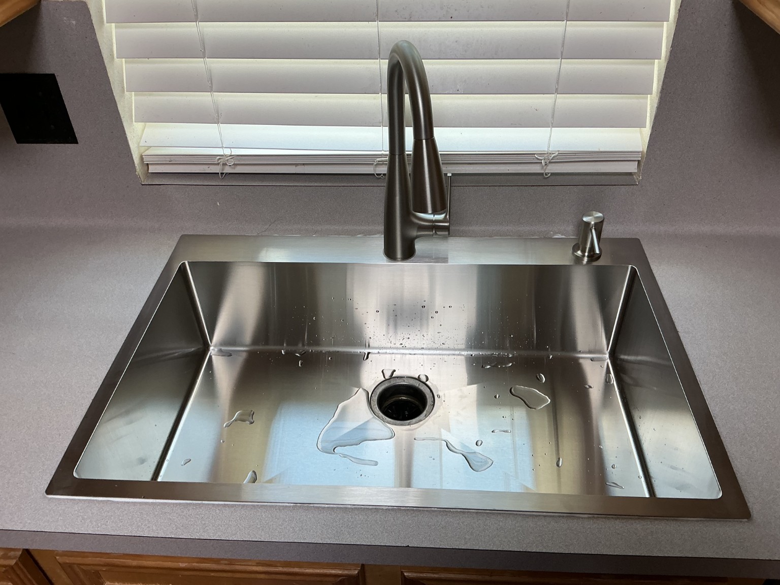 New single-bowl stainless steel kitchen sink and faucet installed in the countertop