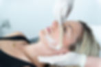Client receiving a facial at O Esthetics, with skincare professional performing treatment in a relaxing, clinical environment