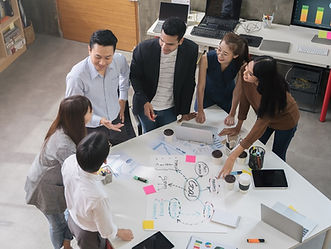 A team huddled around a table as they discuss and point to notes on the table