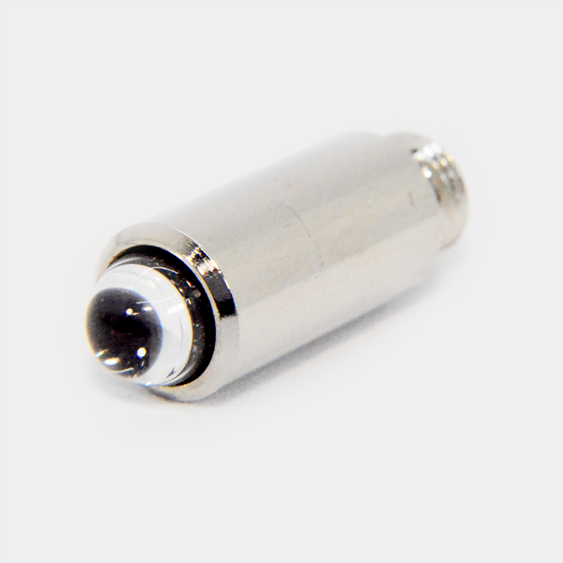 Un componente electrónico cilíndrico plateado con lente transparente sobre fondo gris.