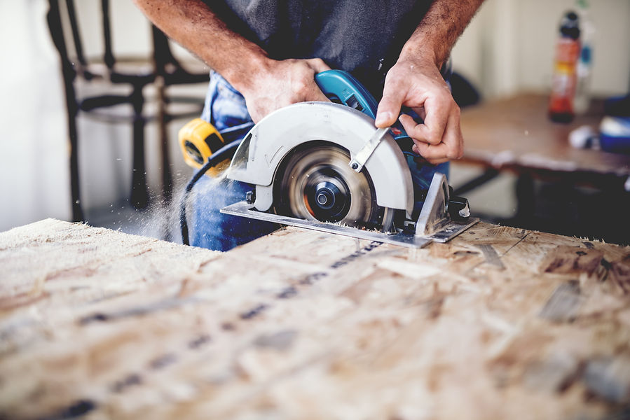 Carpenter using circular saw for cutting wooden boards. Construction details of male worke
