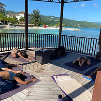 yogis doing yoga pose in an open gazebo near the sea