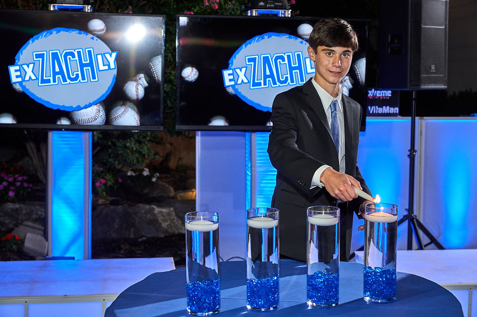 A boy in a suit lights a floating candle in a vase. Blue lighting sets the atmosphere.