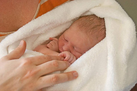 Baby swaddled and midwife holding baby gently