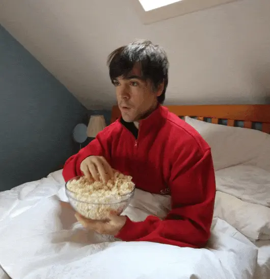 Derek eating popcorn in bed