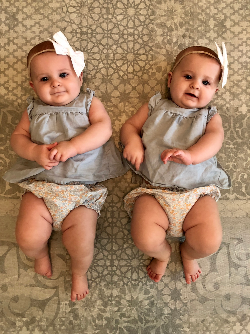 twin girls laying on playmat