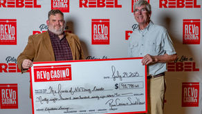 REVO Casino and Social House General Manager Ken Darby and FNHDC’s Board Treasurer Edward O’Reilly hold a check for $98,798.60 from REVO to FNHDC. Photograph by Jon Crean Photography.