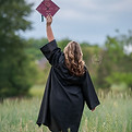 senior girl holding grad cap in field