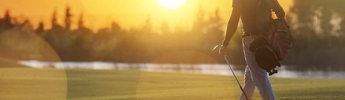 handsome middle eastern golfer carrying bag and walking to next hole at golf course on bea