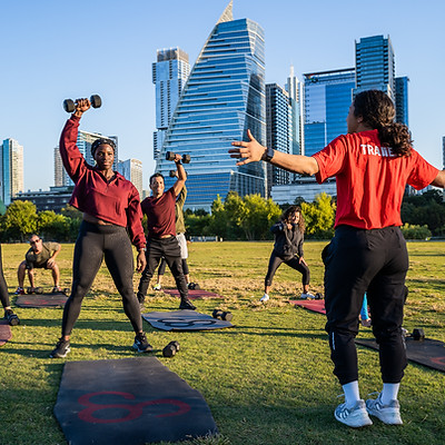 Outdoor workout, people with weights, trainer giving direction, Camp Gladiator training session.