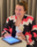 A picture of Rose in a pink and black striped sweater signing a contract on an ipad in a hotel room
