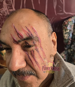 Man with creative and colorful face paint design at a Funky Brush and Palette celebration