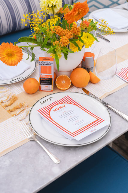 Vibrant tablescape with fresh oranges, bright floral centrepiece, and L’Oréal Men Expert products, photographed by London events photographer Margot Jakobson at the L’Oréal Men’s Staycation retreat.