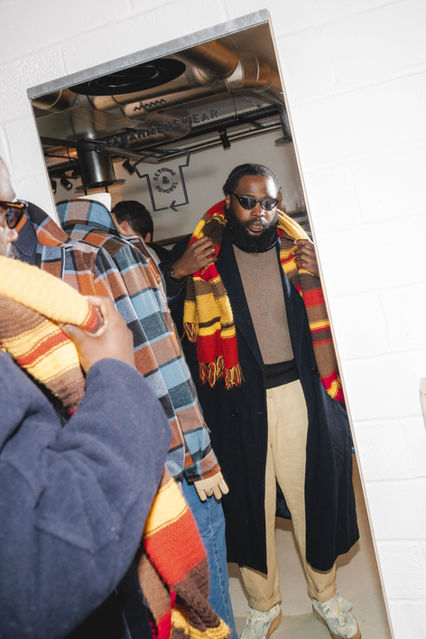 Shot by London event photographer Margot Jakobson at a Farah menswear influencer event in Soho, a stylish man adjusts a bold striped scarf while looking into a mirror, reflecting the brand’s classic yet modern appeal.