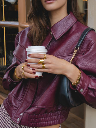 Fashion close-up featuring gold Bohomoon jewellery styled with a burgundy leather jacket, captured by London jewellery photographer Margot Jakobson.