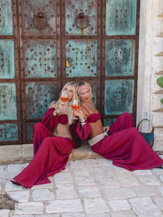 Matching berry co-ords and Aperol spritzes set the mood before ornate Italian doors, an image by London fashion photographer Margot Jakobson on the Komodo-run Musera Puglia trip.
