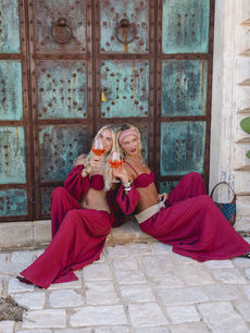 Aperol spritzes in hand before weathered Italian doors, two influencers toast the Musera trip, photographed by brand activations photographer Margot Jakobson with agency Komodo.