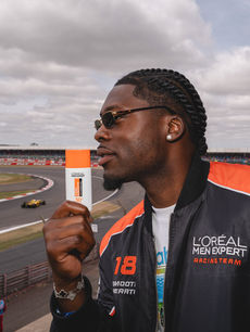 In a portrait by brand activations photographer Margot Jakobson, a guest holds L'Oreal Paris Men Expert SPF50 as a Formula 1 car rounds the Silverstone bend behind him.