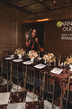 Elegant candlelit dinner setting glows beneath the Garnier Olia branded wall at Carbone London, documented by London events photographer Margot Jakobson for agency Savile Rose.