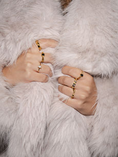 Close-up of stacked gold Bohomoon rings styled with a soft faux fur coat, photographed by London jewellery photographer Margot Jakobson.