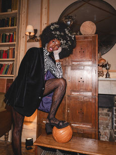 Baby's breath woven through a voluminous afro, a guest in velvet blazer rests a foot on a leather football, image by London events photographer Margot Jakobson for Komodo.