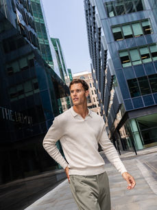 Cream textured knit polo and sage trousers from ICON worn amid London glass towers, photographed by London fashion photographer Margot Jakobson.