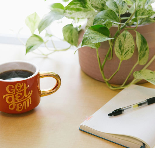 Bureau avec carnet, plantes et tasse de café, illustrant un espace calme propice à la réflexion et à l'accompagnement.