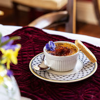 Crème Brûlée Dessert with a Biscuit & Edible Flower placed on a Fine Dining Table