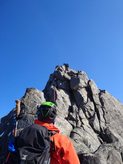 Guide assisting a client on the technical section of Lofoteggen