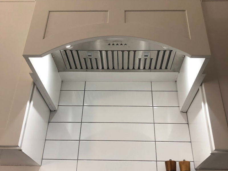 Custom range hood detail with white tile and built-in lighting