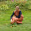Thumbnail: Waldorf teacher with long maroon and mellow yellow crossback apron, gathering apples.