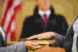 Woman's hand on a bible in front of a judge