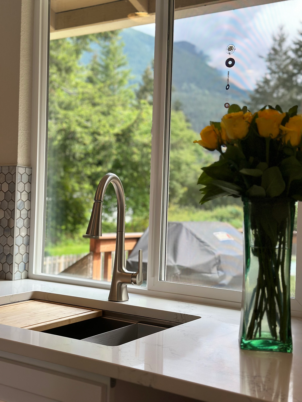 Modern kitchen sink area with large window, quartz countertop, and contemporary cabinetry.