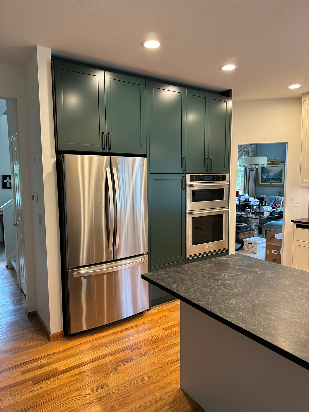 Corner view of remodeled kitchen with gray cabinets, wood flooring, and stainless steel appliances.