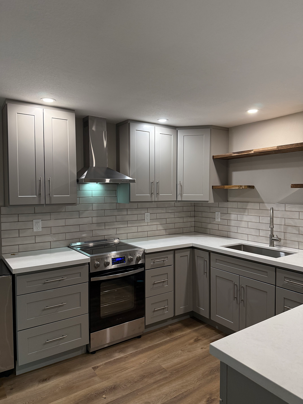 Custom remodeled kitchen with gray cabinets, quartz counters, recessed lighting, and modern finishes.
