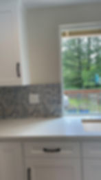 Kitchen corner with modern cabinets, countertop, and window bringing natural light into the space.