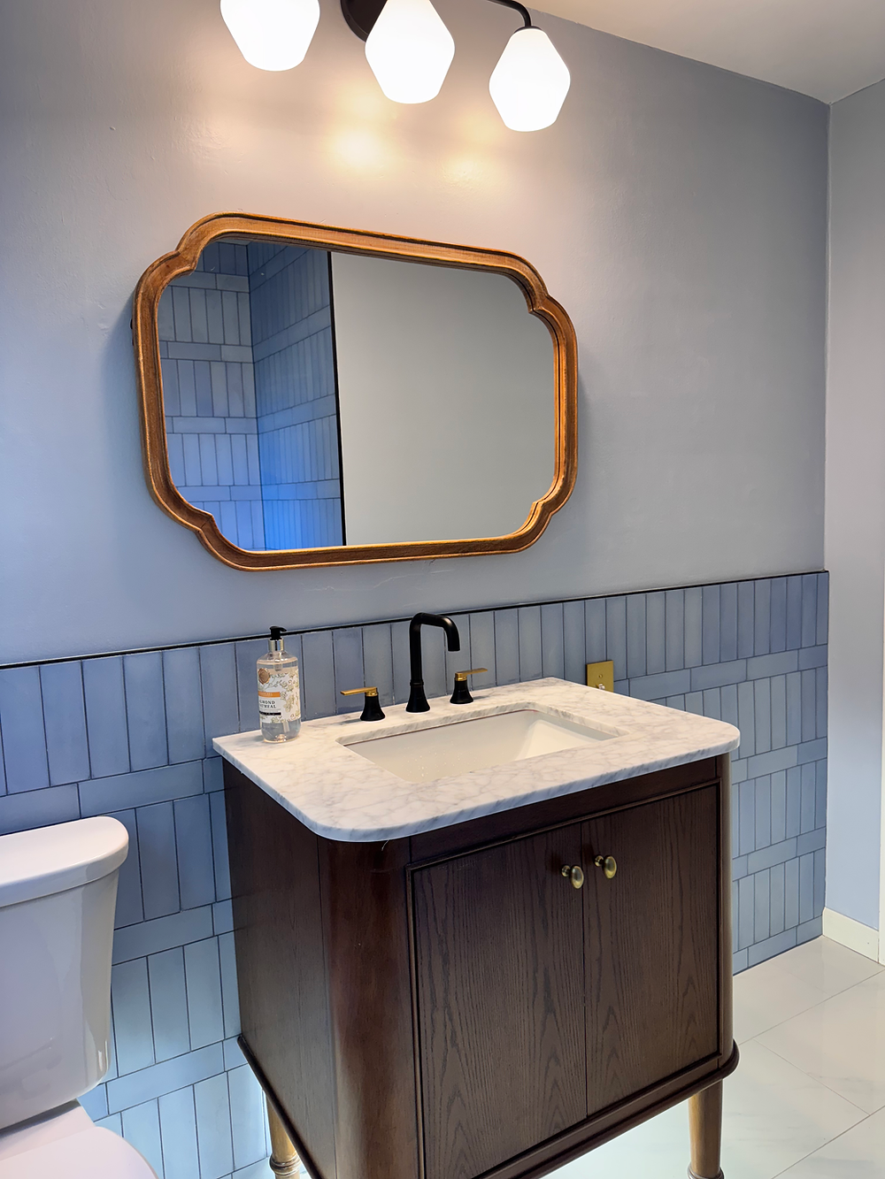 Bathroom vanity with wood cabinet, quartz countertop, and decorative mirror in a cozy remodeled bathroom.