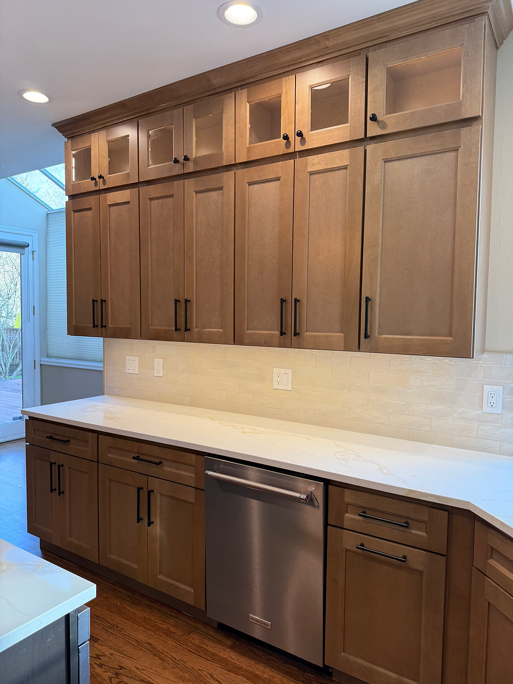 Warm wood kitchen cabinets with quartz counters and modern black hardware in Sammamish kitchen.