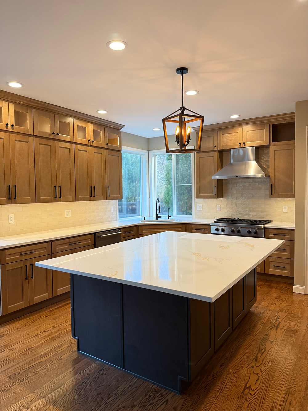 Remodeled Sammamish kitchen with large island, wood cabinets, pendant light, and hardwood floors.