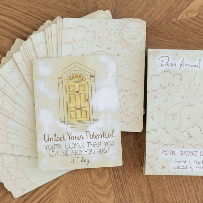 A stack of oracle cards arranged on a brown surface, with envelopes and paper visible.