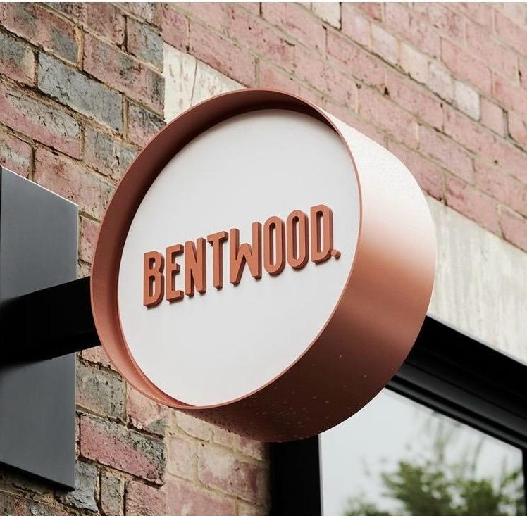 Rótulo redondo Bentwood, solución visual en pared.