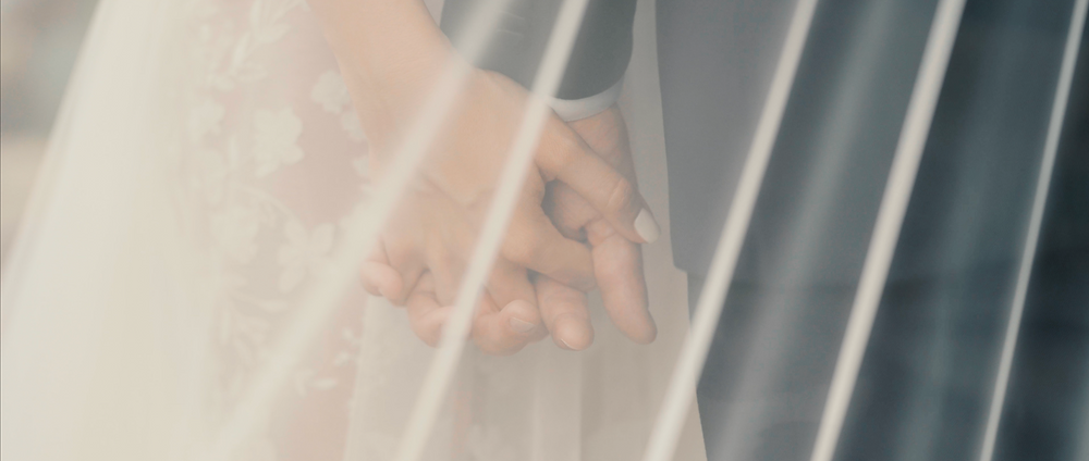 Newlyweds holding hands through the bride's veil during an intimate wedding portrait.