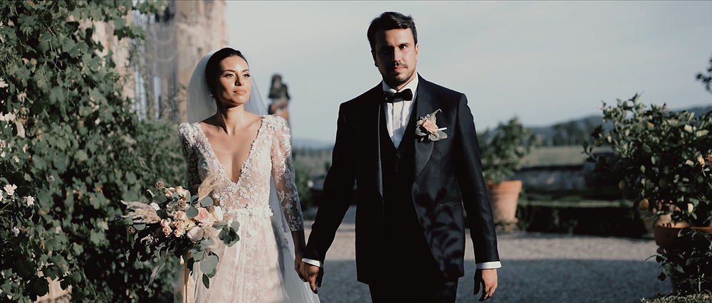 Bride and groom walking through the gardens of a Tuscan villa after their wedding ceremony.