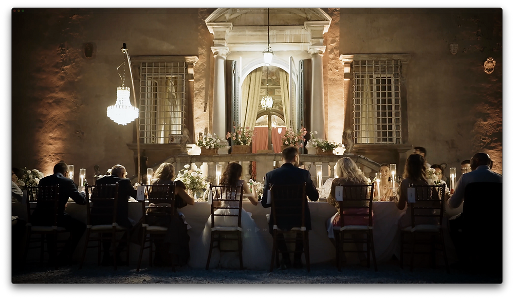 Wedding reception tables arranged in front of a historic Tuscan villa during an outdoor dinner celebration.