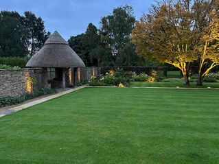 walled garden with thatched pagoda. Uplighting a long walls and in flower beds.