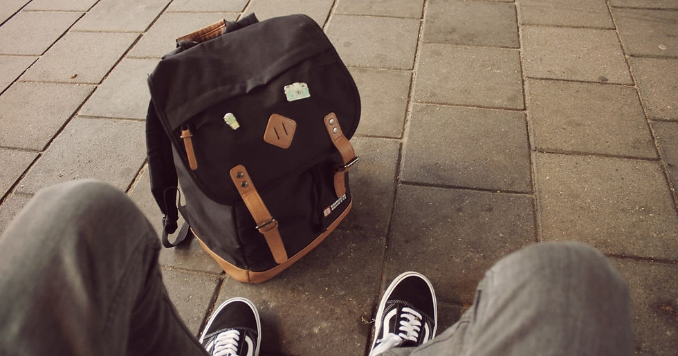 A worn backpack sits on the pavement, capturing a moment of pause for a neurodivergent teen feeling overwhelmed.
